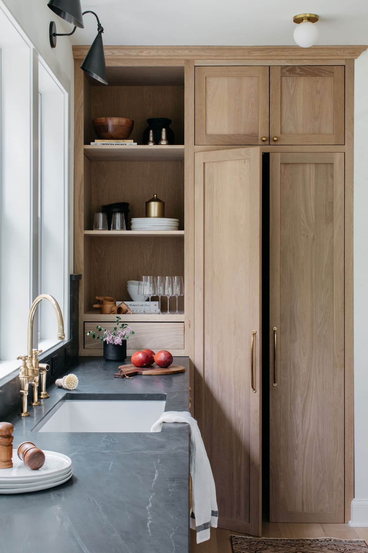 Beautiful kitchen sink and cabinets filled with plates and glasses.